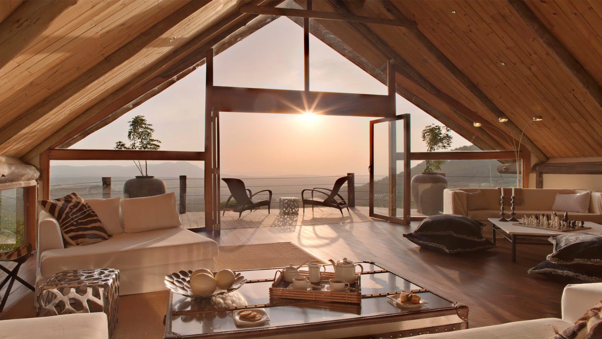 A vintage-style safari camp setup with canvas chairs at sunset.